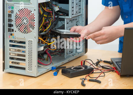Un giovane tecnico che lavora su computer rotto nel suo ufficio Foto Stock