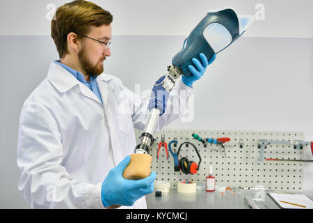 Ritratto di giovane protesi tecnico azienda gamba protesico il controllo di qualità e di effettuare le regolazioni durante il lavoro in laboratorio moderno, c Foto Stock