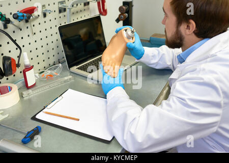 Ritratto di giovane azienda prosthetist gamba protesico il controllo di qualità e di effettuare le regolazioni durante il lavoro in laboratorio moderno, spazio di copia Foto Stock