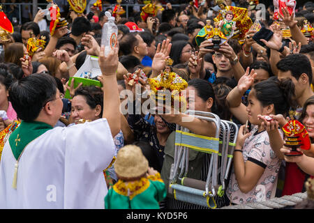 Cebu City, Filippine. 14 gennaio, 2018. Nella forma di una benedizione di un sacerdote docce anticipando la folla con acqua santa.come parte di Il Sinulog 9 giorni di festa religiosa,i cattolici filippini si riuniscono per la mattina presto la messa domenicale portando con loro Santo Nino figurine,repliche di Gesù bambino.La credenza in questa effige risale al tempo di explorer Ferdinand Magellan che ha dato la statuetta originale come un dono quando ha atterrato nel 1521 a Cebu. Credito: galleria immagini2/Alamy Live News Foto Stock