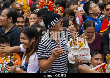 Cebu City, Filippine. 14 gennaio, 2018. Un uomo attende con il suo Santo Nino figurine nella speranza che essi saranno cosparsi e benedetta dai sacerdoti con acqua santa.come parte di Il Sinulog 9 giorni di festa religiosa,i cattolici filippini si riuniscono per la mattina presto la messa domenicale portando con loro Santo Nino figurine,repliche di Gesù bambino.La credenza in questa effige risale al tempo di explorer Ferdinand Magellan che ha dato la statuetta originale come un dono quando ha atterrato nel 1521 a Cebu. Credito: galleria immagini2/Alamy Live News Foto Stock