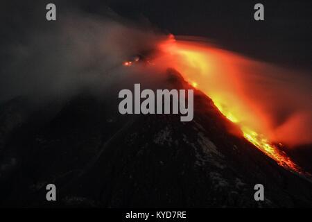 Karo, nel nord di Sumatra, Indonesia. Xiv gen, 2018. Flussi di Lava come il monte Vulcano Sinabung fuoriesce al rossastro ceneri vulcaniche in Karo, Nord Sumatra on gennaio 13, 2018 a mezzanotte. Il monte Sinabung ruggito torna alla vita nel 2010 per la prima volta in 400 anni, dopo un altro periodo di inattività è scoppiata una volta di più nel 2013, ed è rimasta altamente attivo dal. Credito: Ivan Damanik/ZUMA filo/Alamy Live News Foto Stock