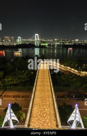 Vista notturna di Urban Skyline, compreso il Rainbow Bridge e Odaiba, un quartiere di shopping su un'isola artificiale nella Baia di Tokyo, Tokyo, Giappone, con barche yakatabune visibile, Ottobre 26, 2017. () Foto Stock