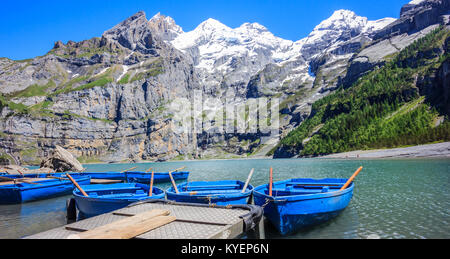 Sunny attività estive e la ricreazione, canottaggio barche blu mentre godendo di bellissime Alpi Svizzere vista sul lago Oeschinen (Oeschinensee), vicino a Kandersteg, Foto Stock