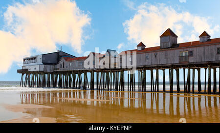 Old Orchard Beach, Maine. Il molo in legno su palafitte in acqua con edifici storici mostrato in una giornata di sole con cielo blu e ondeggianti nuvole bianche. Foto Stock