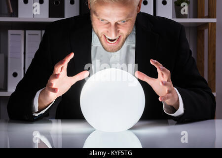 Giovane Imprenditore guardando al futuro in una sfera di cristallo in Office Foto Stock