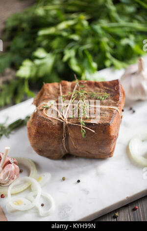 Frammento di salata lardo affumicato in garza con una corda.tradizionale russo e ucraino pasto.il cibo sano con pranami spezie, erbe, cipolla e aglio.Food Foto Stock