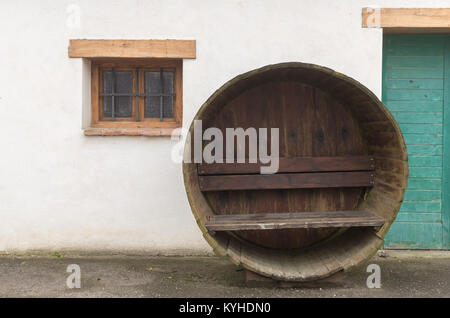 Banco in una vecchia botte di vino davanti a una vecchia casa, Austria Foto Stock