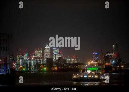 Il Woolwich Ferry attraversa il fiume Tamigi con il quartiere finanziario di Londra in background. Foto Stock