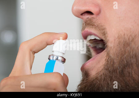 Close-up di una mano di un uomo la spruzzatura di respiro rinfrescante Foto Stock