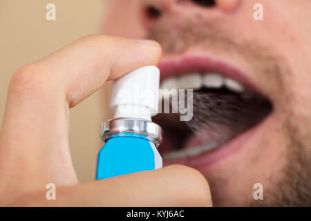 Close-up di una mano di un uomo la spruzzatura di respiro rinfrescante Foto Stock