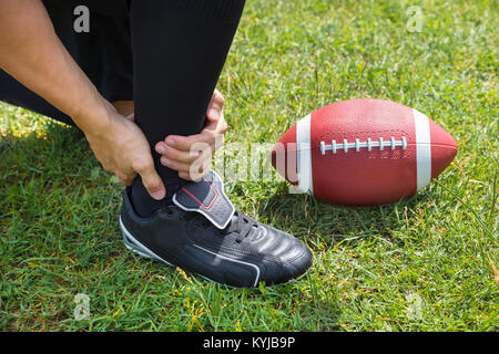 Vista in elevazione del giocatore di football americano con dolore nella sua caviglia sul campo Foto Stock