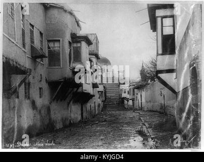 Questa fotografia raffigura una scena di strada a Damasco, in Siria, dalla collezione Library of Congress (LCCN 2001704581). Mostra l'architettura tradizionale e la vita urbana nel quartiere storico della città. Foto Stock