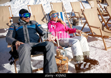 Coppia felice ridere e rilassarsi in prendisole in montagne in inverno Foto Stock