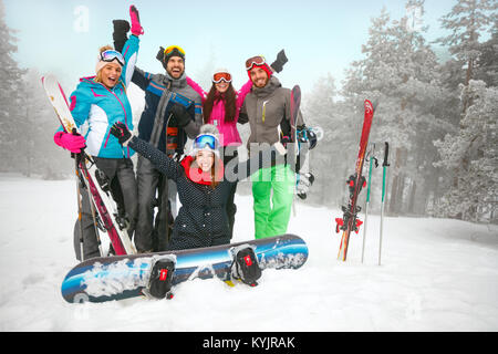 Il gruppo di allegro amici sciatori e snowboarder divertirsi su snowbound foresta invernale Foto Stock