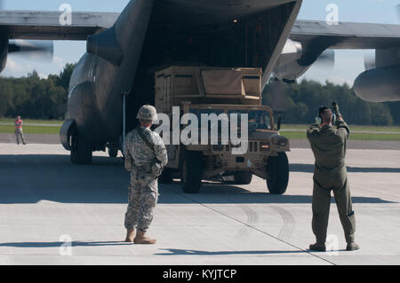 Air Force Tech. Sgt. Paul Jones (a destra), un loadmaster con il Kentucky Air National Guard's 123Airlift Wing, dirige lo scarico del carico da un Kentucky C-130 Hercules come il velivolo attende di discostarsi un aeroporto in Lettonia il 7 settembre 6, 2014, durante l'operazione di giunzione Saber. La 123hanno partecipato all'esercizio di formazione insieme ad altri cinque Aria Unità di Protezione e di truppe provenienti da 17 paesi della NATO. (U.S. Air National Guard Photo da 2 Lt. James W. Killen) Foto Stock