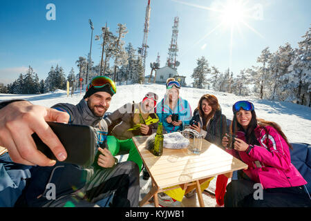 Gruppo di amici a ridere e godere nella bevanda presso ski resort insieme Foto Stock