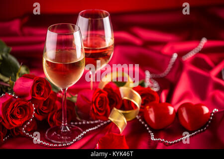 Valentines o il concetto di matrimonio. Bicchieri di vino rose rosse e romantico per due in rosso. Biglietto di auguri per il giubileo o anniversario. Foto Stock