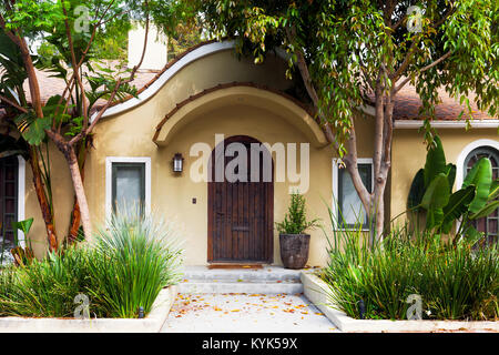 Mediterraneo moderno esterno della casa di Los Angeles. Sportello anteriore fiancheggiata da piante tropicali. Per sopracciglia arcuate tenda Foto Stock