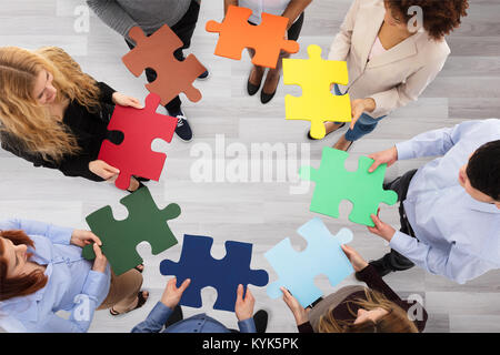 Vista in elevazione del Business Persone azienda colorato i puzzle in Office Foto Stock