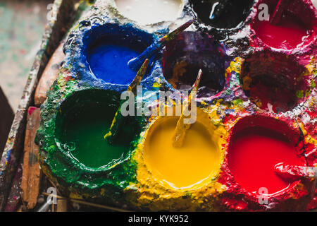 Rosso, giallo, blu e verde sono i colori per la pittura in laboratorio artigiano, creatività autentica nozione, primo piano Foto Stock
