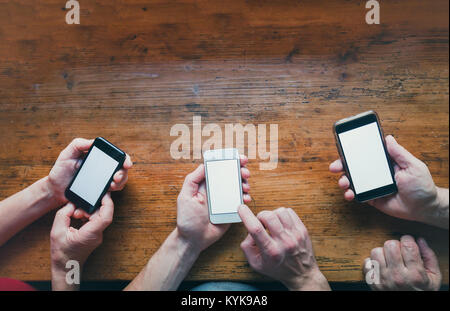 Social networking concetto, molte mani con gli smartphone gadget su sfondo di legno Foto Stock