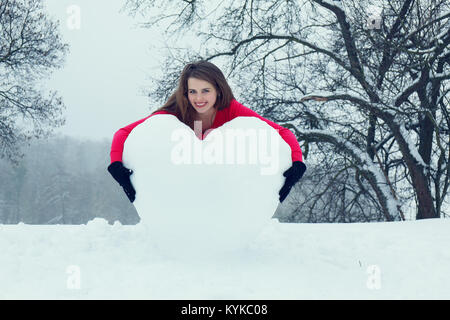 Donna che abbraccia il cuore dalla neve Foto Stock