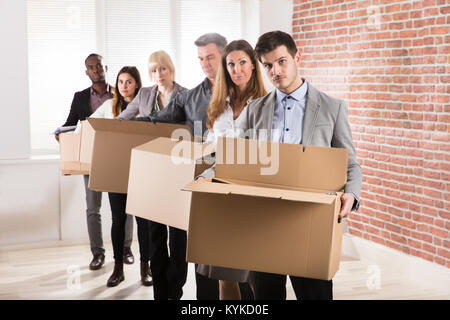 Fila di diversi imprenditori in piedi con le scatole di cartone in Office Foto Stock