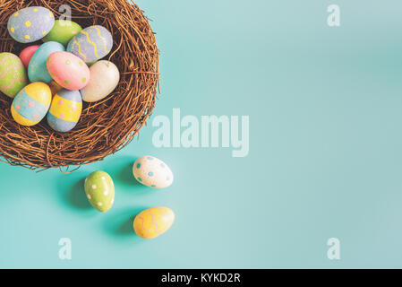 Coloeful uova di pasqua nel nido su color pastello sfondo con lo spazio. Foto Stock