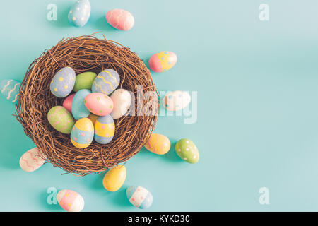 Coloeful uova di pasqua nel nido su color pastello sfondo con lo spazio. Foto Stock