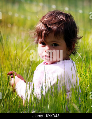 Carino piccolo ragazza in bokeh molla verde dei prati Foto Stock