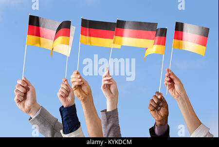 Mani bandiera tedesca contro il cielo blu Foto Stock