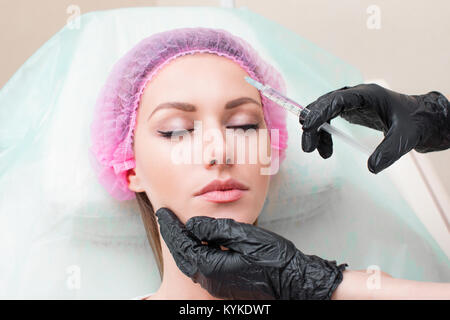 Trattamento cosmetico. Closeup estetista mani facendo la pelle del viso sollevamento di iniezione al volto di donna. Femmina con gli occhi chiusi la ricezione di bellezza. Biorevital Foto Stock