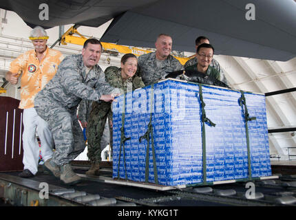 ANDERSEN AIR FORCE BASE, Guam (dec. n. 11, 2017) Il Mag. Gen. Christopher Bence, commander, U.S. Aria forza expeditionary, centro sinistra, posteriore Adm. Shoshana Chatfield, commander, regione di giunzione Marianas e altri alti dirigenti spingere un pallet nel retro di un C-130J Super Hercules durante l'operazione di caduta di Natale cerimonia Push a bordo di Andersen Air Force Base dic. 11. Ora nella sua 66esima iterazione, operazione caduta di Natale porta la tradizione di confezionamento e distribuzione di cibo, strumenti, giocattoli e altri elementi utili per i residenti nella Repubblica della Mariana Islands settentrionale, Stati Federati di Microne Foto Stock