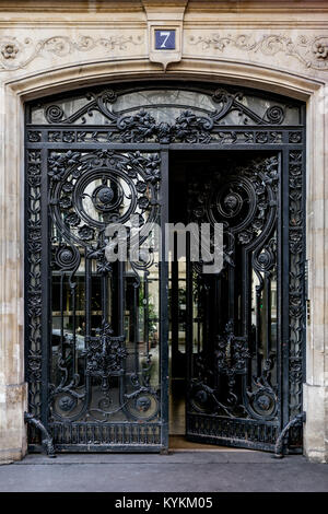 Parigi art nouveau in ferro e vetro porte doppie in un raffinato design. Una porta è parzialmente aperta dalla strada. Il numero di riferimento 7. Foto Stock