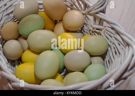 Di diverso colore le uova di Pasqua mostrato in un bianco cesto in vimini Foto Stock