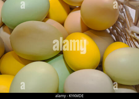 Di diverso colore le uova di Pasqua mostrato in un bianco cesto in vimini Foto Stock