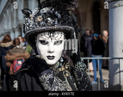 Venezia, Italia - 18 febbraio 2017: Ritratto di una donna non identificato usura vintage costume nero, guanti, cappello e maschera bianca e posa su San Marco. Foto Stock