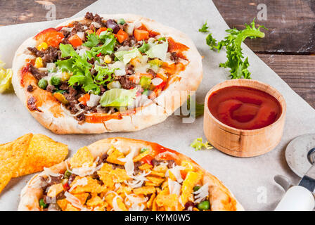 In casa Mexican Taco PIzza con Nachos chips, fagioli, verdure fresche, carni bovine, spazio di copia Foto Stock