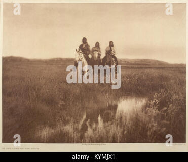 Fotografia di Edward S. Curtis che mostra tre nativi americani a cavallo, parte della nazione Sioux, che cavalcano attraverso le pianure. L'immagine cattura il loro abbigliamento tradizionale e l'ampio paesaggio della prateria. Foto Stock