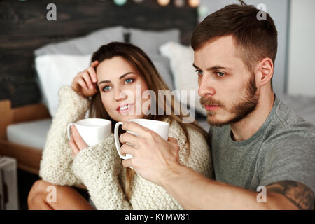 Giovane con caffè seduti sul pavimento in camera da letto Foto Stock