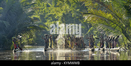 Canoa cerimonia di guerra di Asmat persone. Cacciatori di teste di una tribù di Asmat spear-oar in pitture di guerra. Nuova Guinea Isola, Indonesia. Maggio 23, 2016 Foto Stock