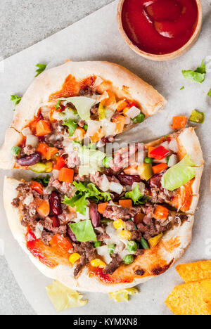 In casa Mexican Taco PIzza con Nachos chips, fagioli, verdure fresche, carni bovine, spazio di copia Foto Stock