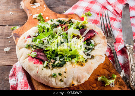 Pizza Vegan con verdure fresche e pesto, sullo sfondo di legno, spazio di copia Foto Stock