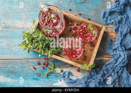 Bevanda a base di mirtillo palustre con la menta, ghiaccio e frutti di bosco in una casella su vintage sfondo di legno, vista dall'alto Foto Stock