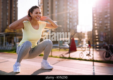 Giovane donna facendo squat in area urbana Foto Stock