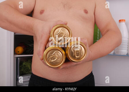 Uomo in possesso di tre lattina di birra sul frigorifero sfondo. Uomo vicino al frigorifero. Foto Stock