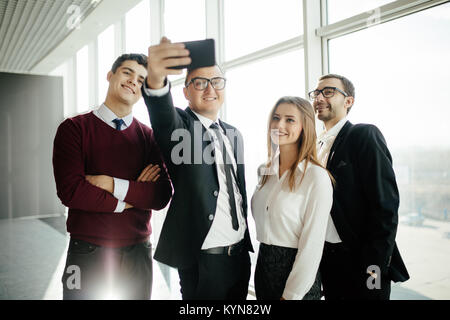 Giovane e bella gente di affari stanno facendo selfie utilizzando uno smart phone in office Foto Stock