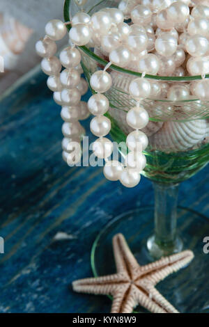 Il Pirate's Treasure - perle bianche e gusci blu su sfondo di legno, vintage fashion concept Foto Stock