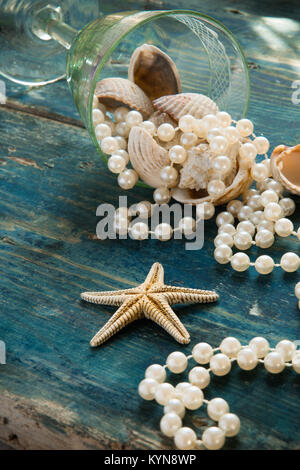 Il Pirate's Treasure - perle bianche e gusci blu su sfondo di legno, vintage fashion concept Foto Stock